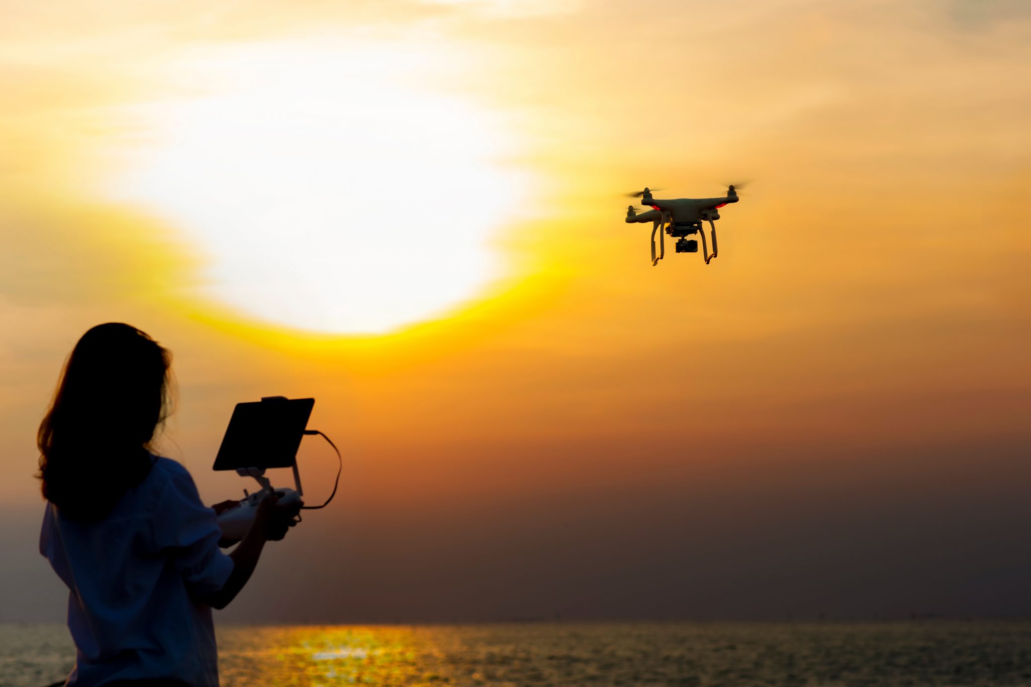 Girl,Operating,A,Drone,With,Remote,Control.,Dark,Silhouette,Against